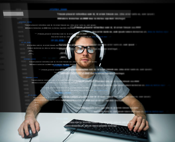 man in headset hacking computer or programming