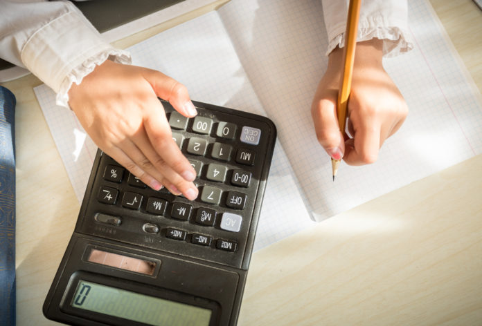 girl solving maths task on calculator